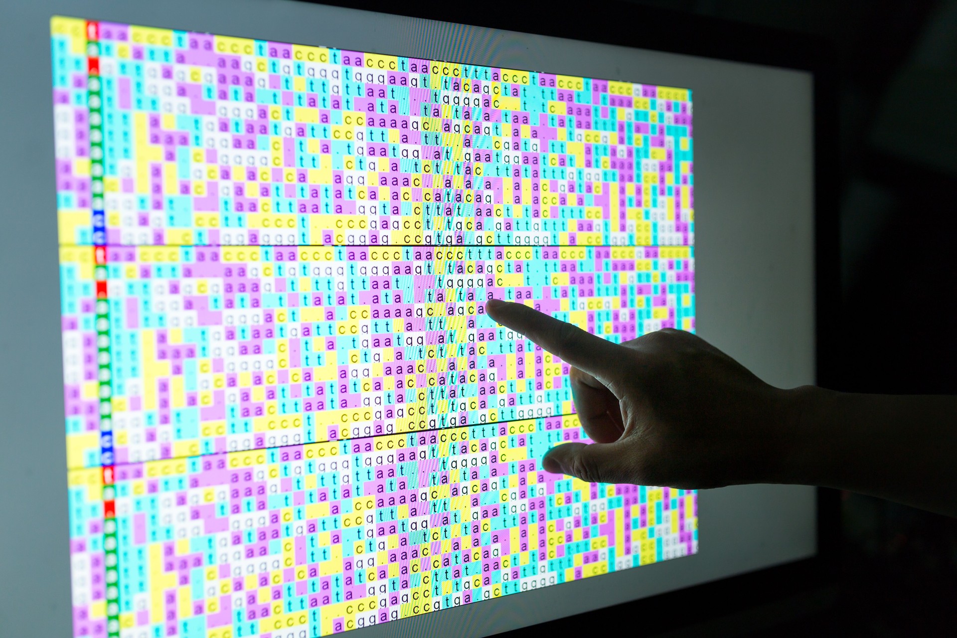 DNA code on screen with hand point to the screen